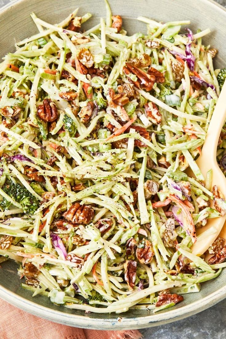 a bowl filled with broccoli and nuts next to a wooden spoon