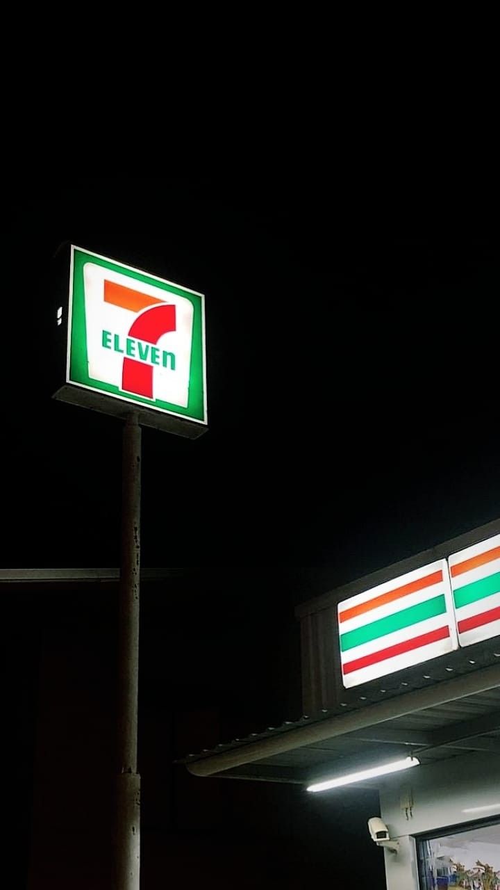 a seven eleven gas station at night with the sign lit up in red, white and green