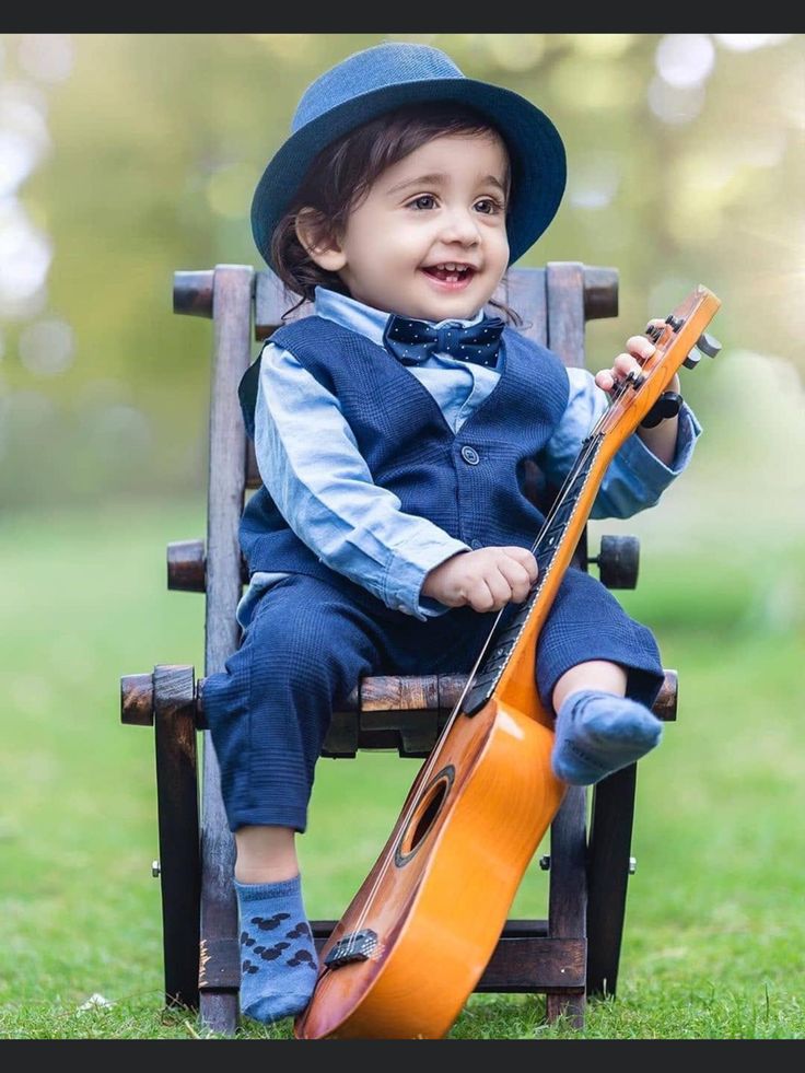 a little boy sitting in a chair with a guitar