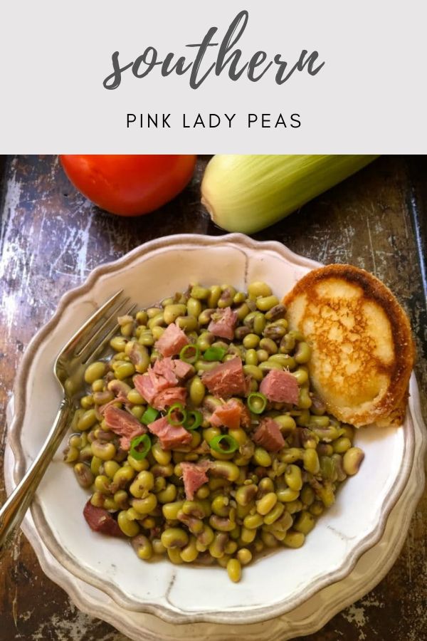 a white bowl filled with peas and ham next to some bread on top of a table