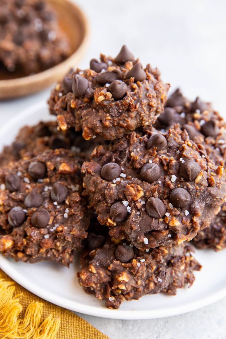 chocolate cookies stacked on top of each other on a white plate next to a wooden spoon