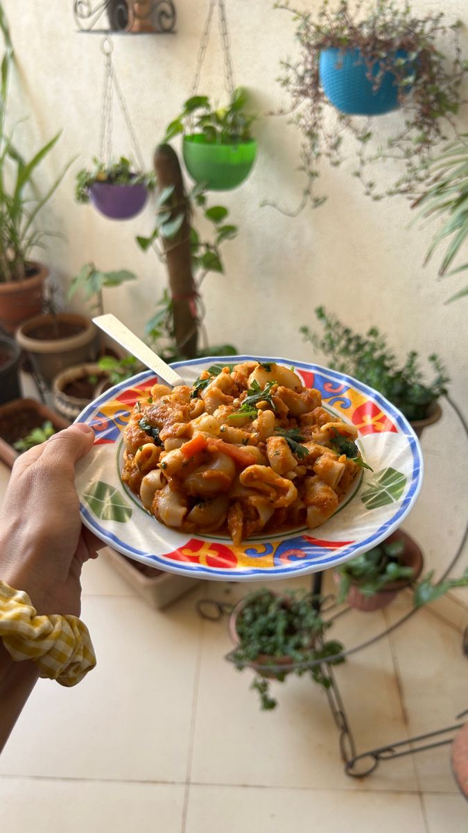 a person holding a plate with food on it in front of some potted plants