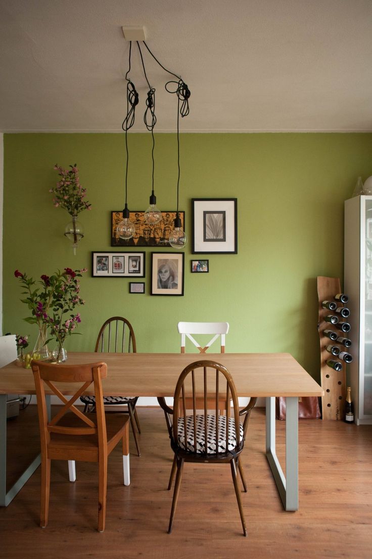 a dining room with green walls and pictures on the wall