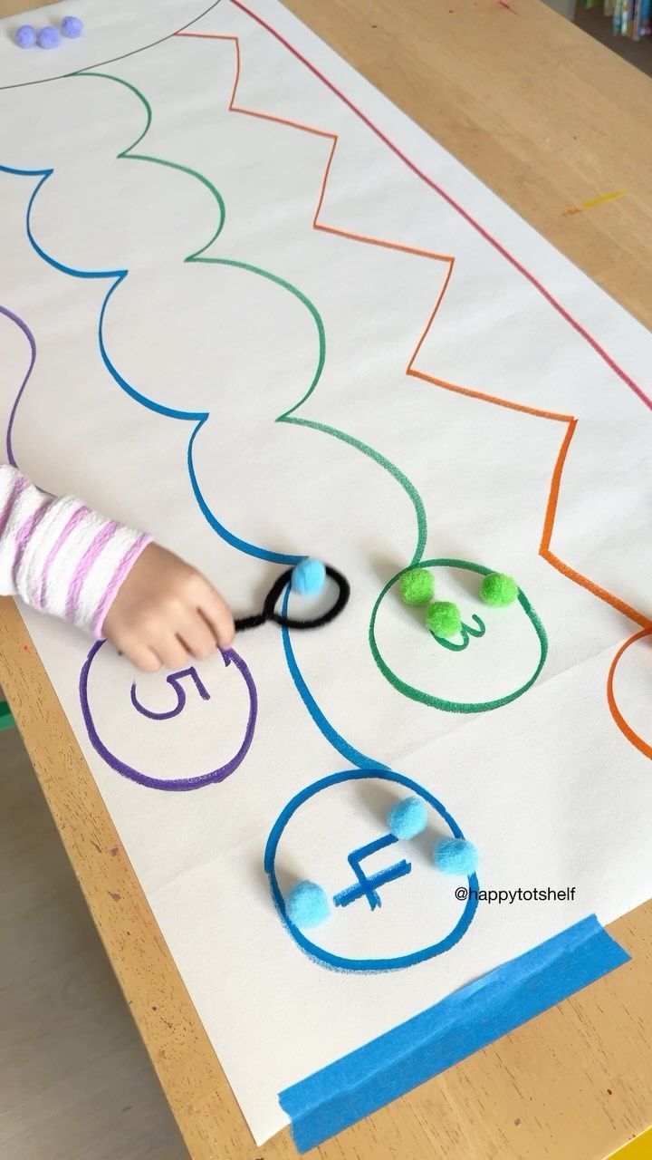 a young child using scissors to cut out letters on a large sheet of paper