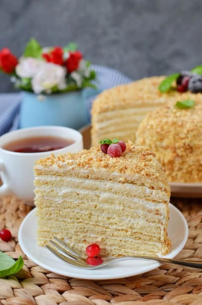 a piece of cake on a plate with a fork and cup of tea next to it