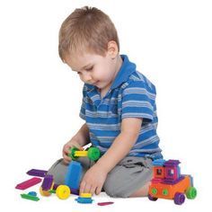 a young boy playing with toys while sitting on the floor in front of white background