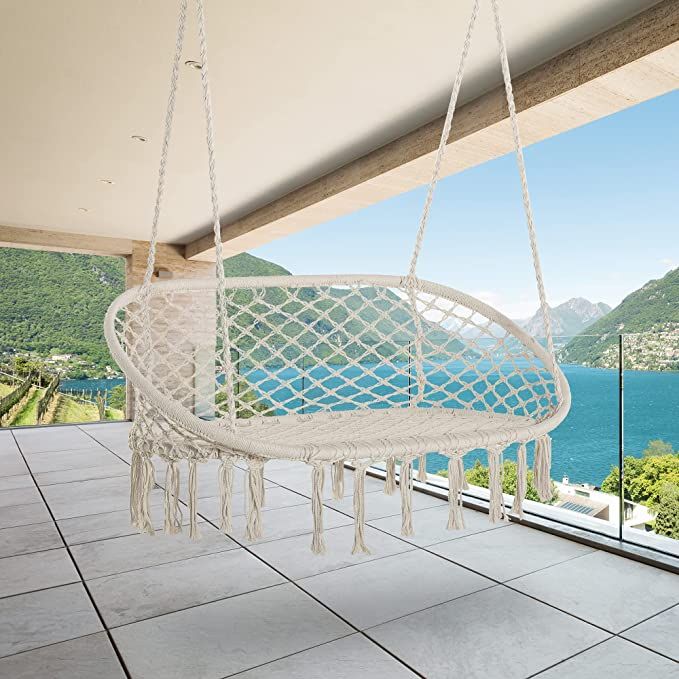 a white hanging chair on a porch overlooking the ocean