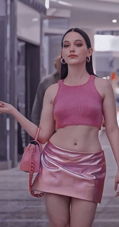 a woman walking down the street wearing a pink skirt and crop top with her handbag