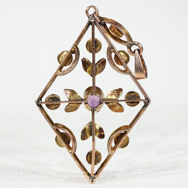 During the Edwardian era, feminine motifs with delicate yet understated designs were considered en vogue. Natural pearls, amethysts, peridots, aquamarines, and other semi-precious stones were worn by affluent women to complement the trend of donning white silk and lace. This jewelry movement differed from the larger and dark colored jewels of the later Victorian era, it was a fresh and welcome change that breathed life back into fashion. This pendant would have been incredibly stylish for its ti Victorian Yellow Gold Jeweled Jewelry, Antique Yellow Gold Jewelry With Rose Cut Diamonds, Art Nouveau Rose Gold Jewelry As Gift, Art Nouveau Rose Gold Jewelry Gift, Art Nouveau Rose Gold Jewelry As A Gift, Art Nouveau Rose Gold Jewelry For Gift, Rose Gold Art Nouveau Jewelry For Gift, Antique Round Amethyst Jewelry, Victorian Amethyst Round Jewelry