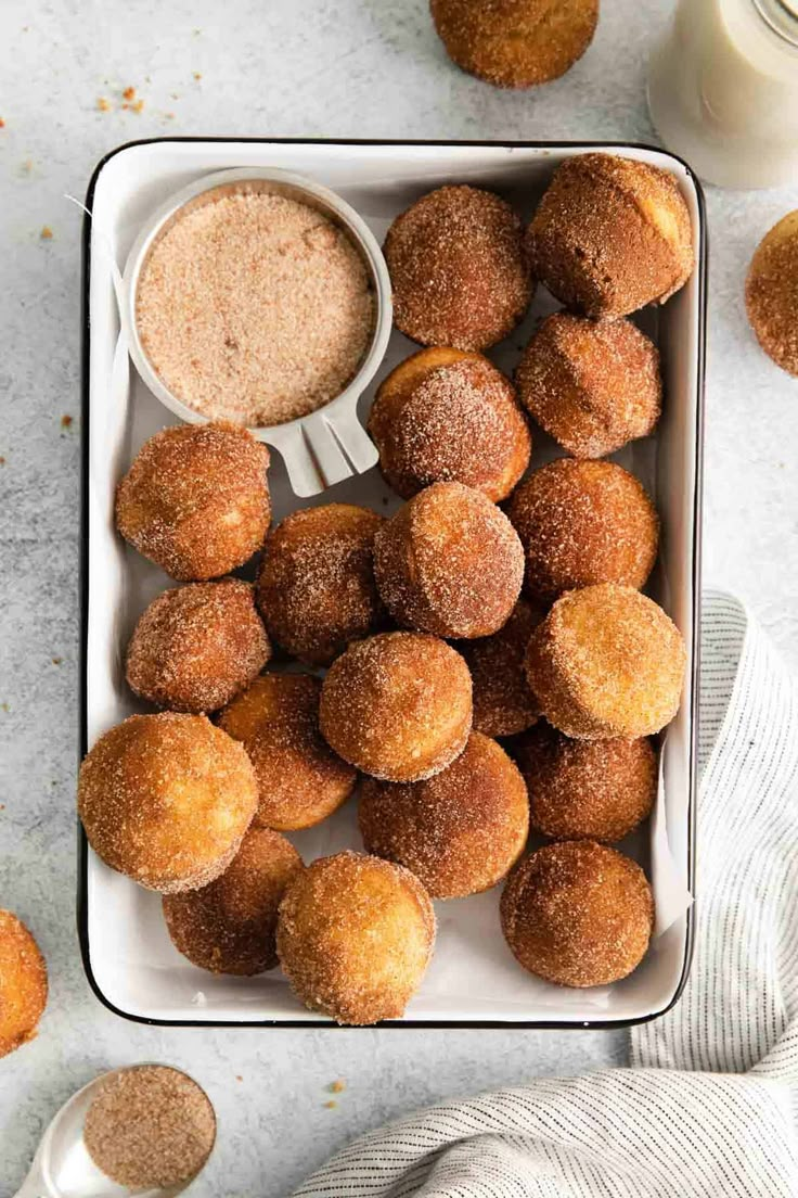 sugared donuts in a white dish with a cup of coffee on the side