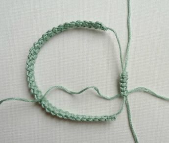 a close up of a piece of green string on a white surface with a knot in the middle