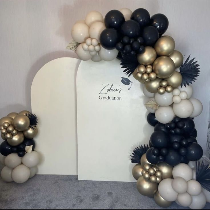 an arch made out of balloons and black and white decorations for a graduation party or celebration