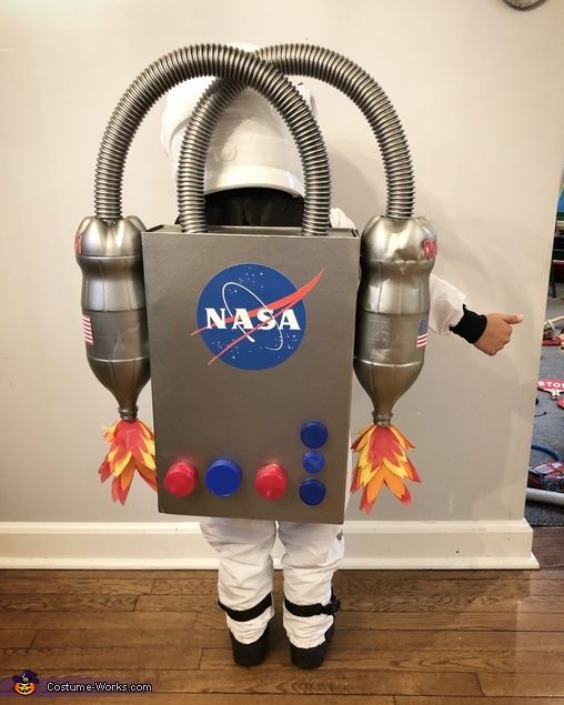 a young boy dressed up as an astronaut in front of a nasa sign on the wall