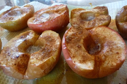 apples and cinnamon donuts sitting on top of a piece of wax paper