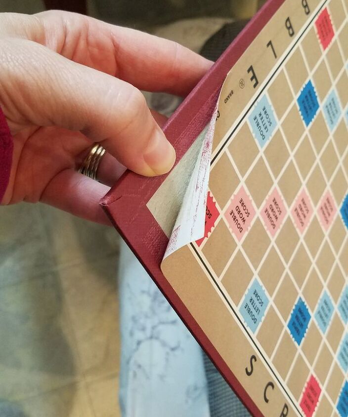 a person holding onto a scrabble board