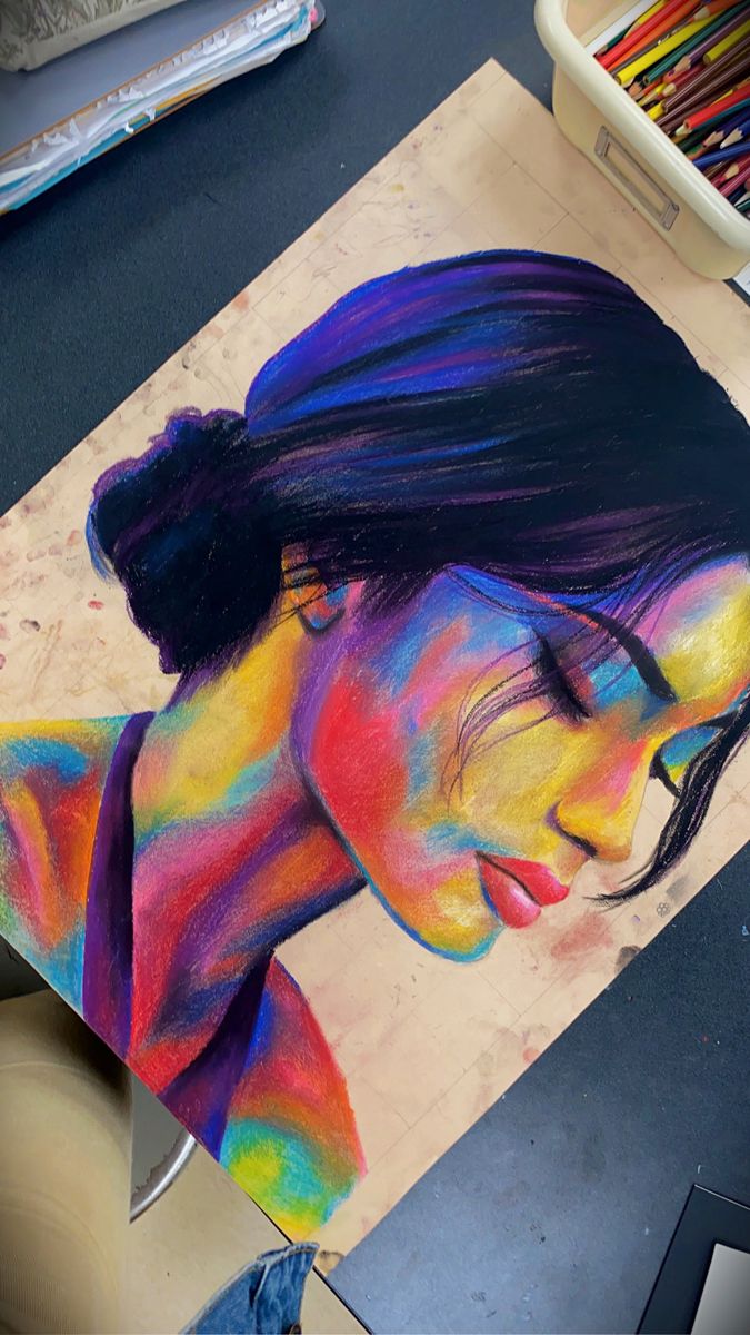 a woman's face is painted with colored pastel pencils on a table