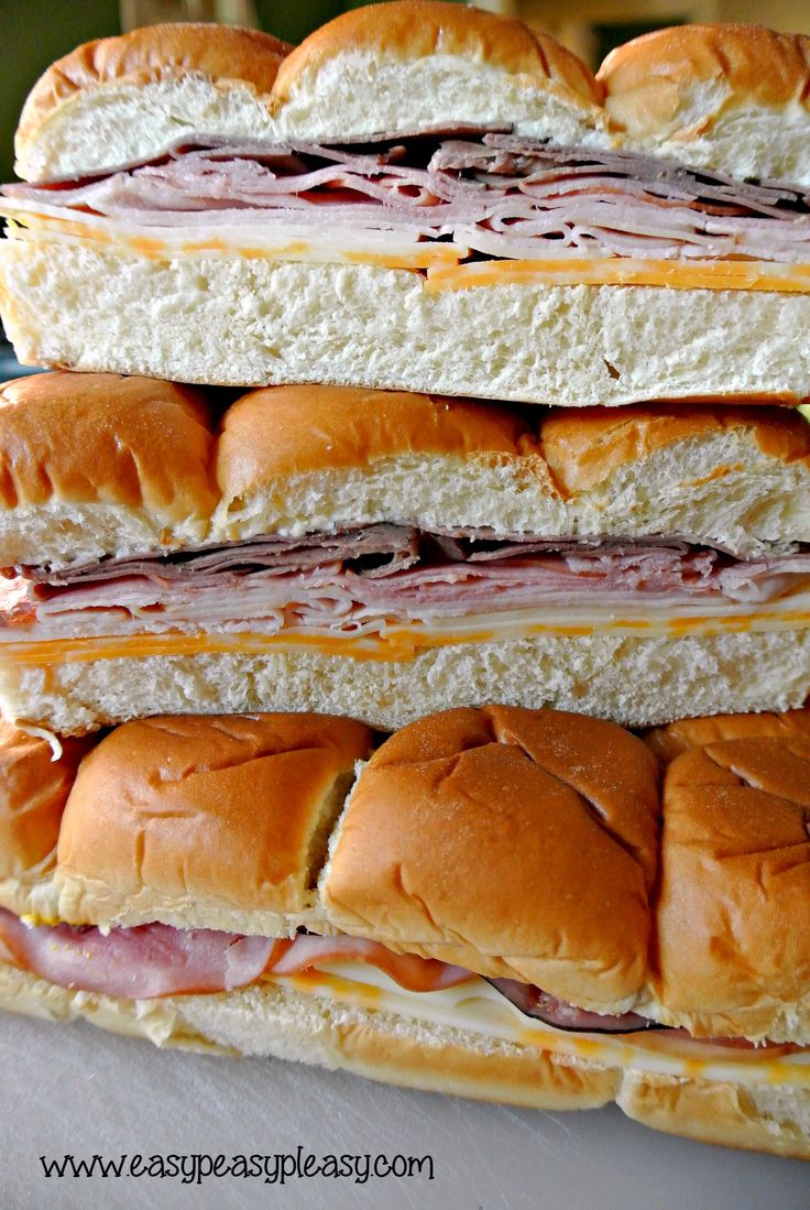 three sub sandwiches stacked on top of each other with ham and cheese in between them