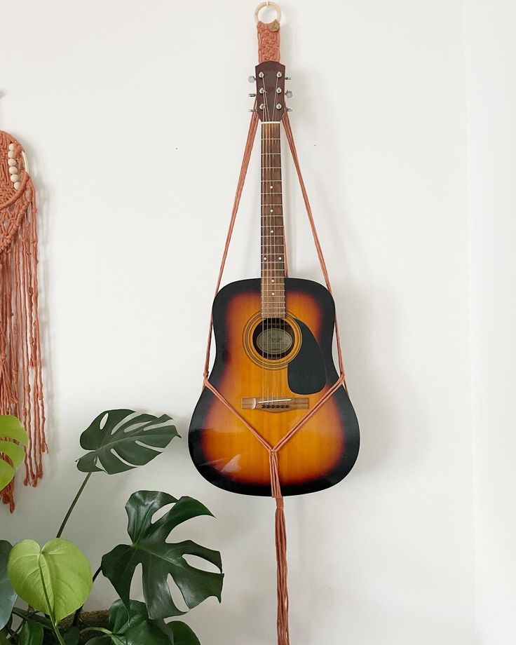 a guitar hanging on the wall next to a potted plant