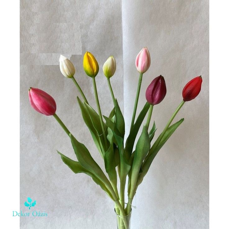 a vase filled with colorful tulips sitting on top of a white tablecloth