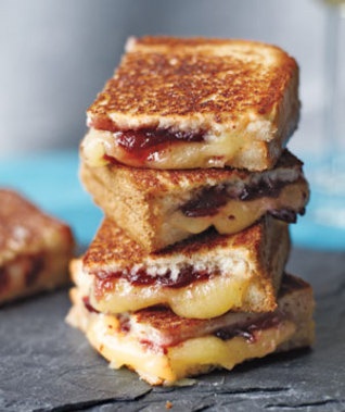 four grilled cheese sandwiches stacked on top of each other with jam in the middle