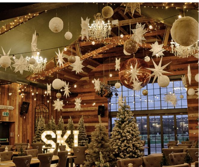 christmas decorations are hanging from the ceiling in a large room with wooden walls and ceilings