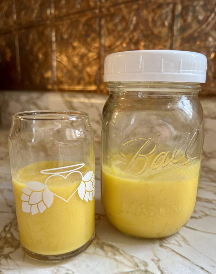 two jars with yellow liquid sitting on a counter