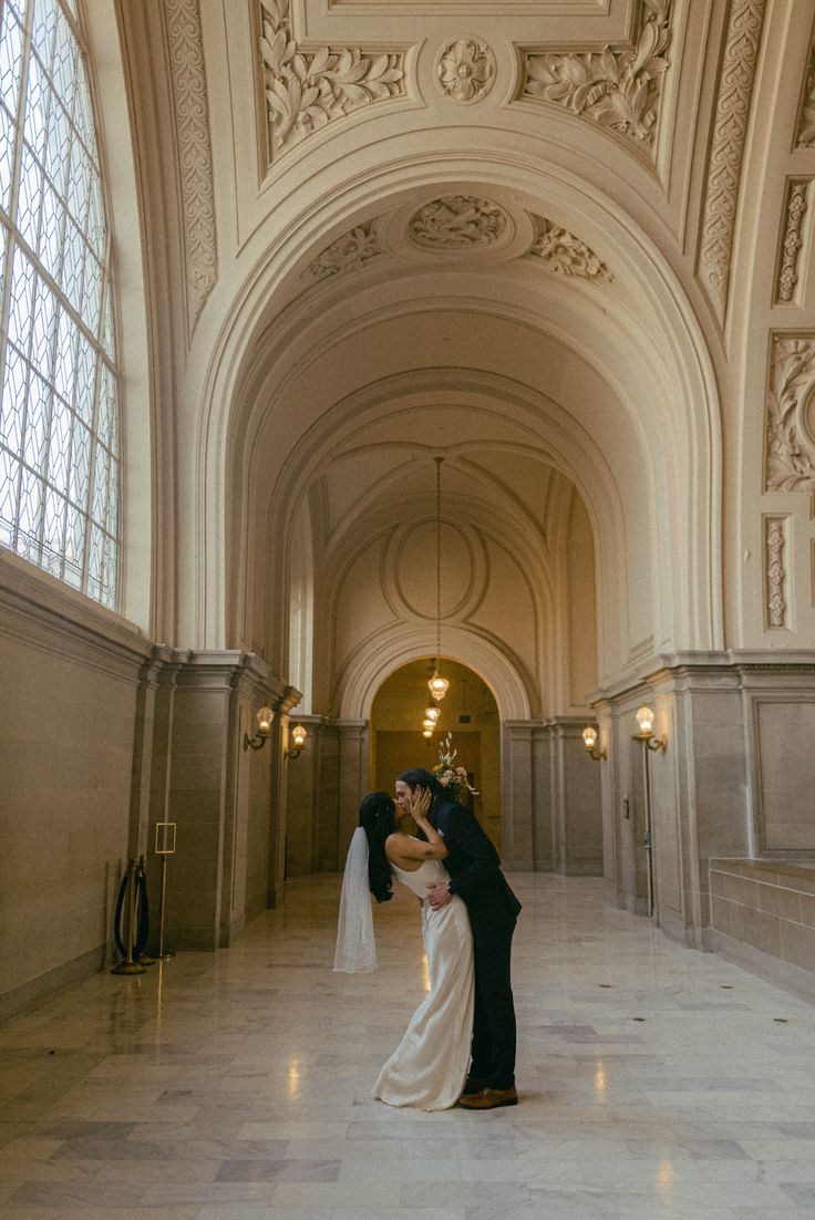 a bride and groom kissing in an ornate building