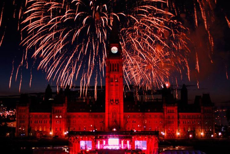 fireworks are lit up in the night sky over a large building with a clock tower