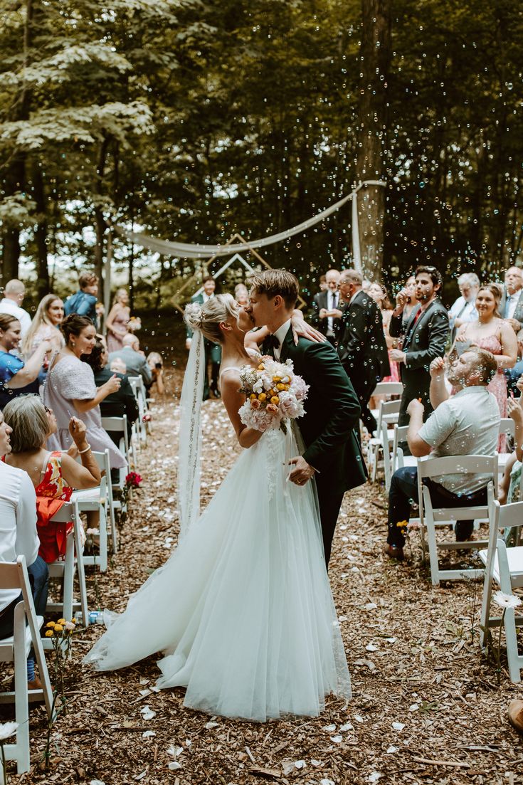 a bride and groom kiss as they walk down the aisle at their outdoor wedding ceremony