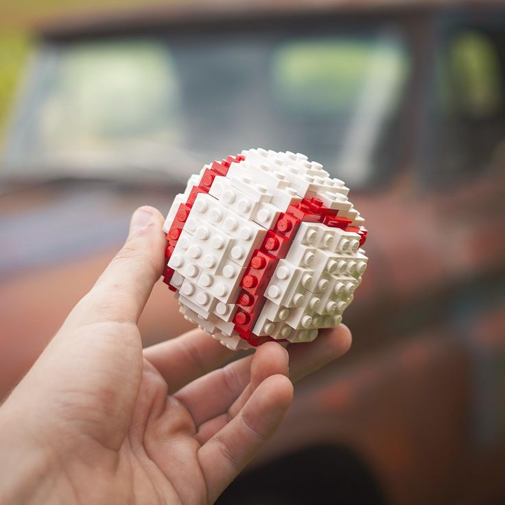 a hand is holding a ball made out of legos in front of a truck