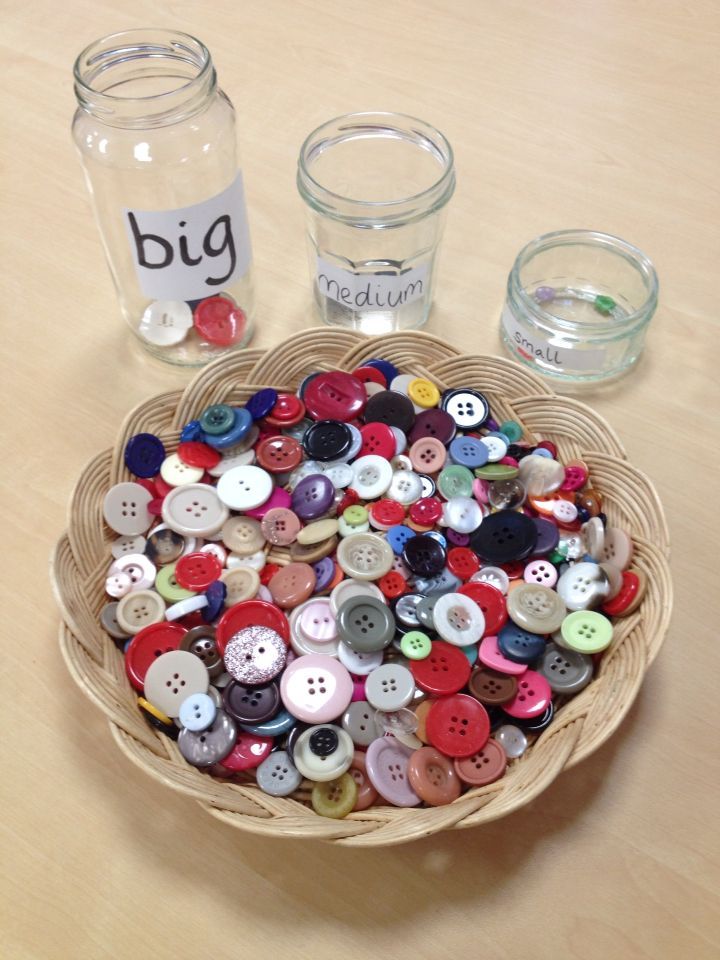 a basket filled with lots of different colored buttons next to two mason jars on a table