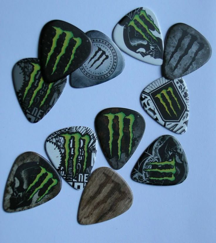 six guitar picks with the monster logo painted on them, all in different shapes and sizes