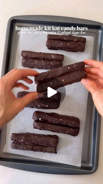 two hands reaching for chocolate candy bars on a baking tray