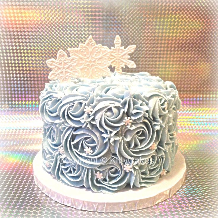 a blue cake with white frosting and flowers on it's top sitting on a table