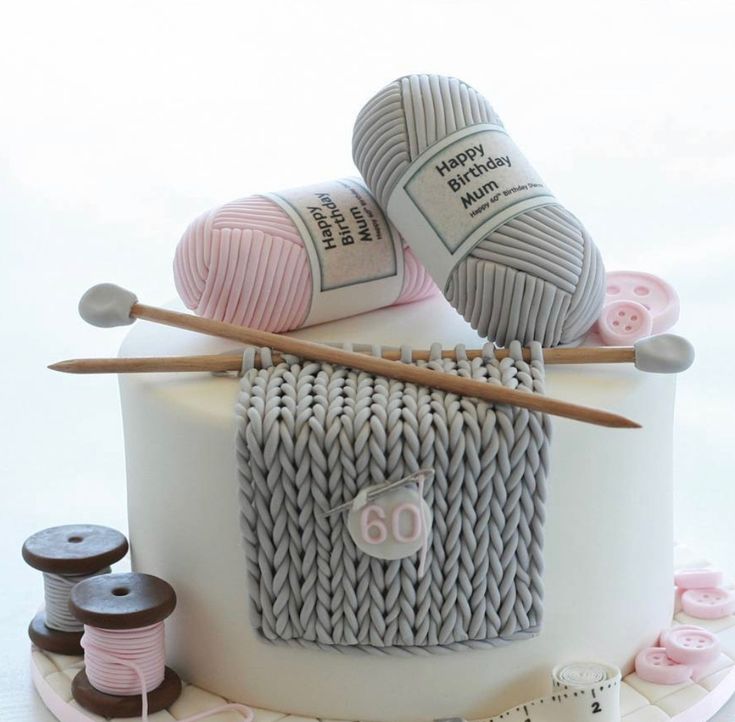 a birthday cake decorated with yarn and knitting needles