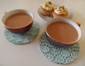 two cupcakes and a bowl of hot chocolate on a doily