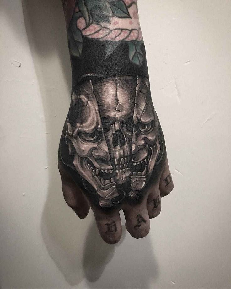 a man's hand with a skull and roses tattoo on the left arm,