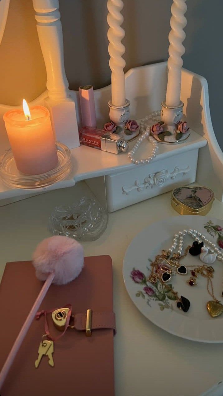 a white table topped with lots of jewelry and a lit candle on top of it