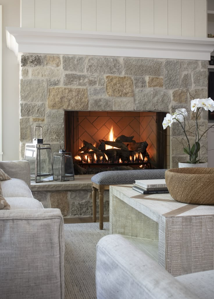 a living room filled with furniture and a fire place in front of a stone fireplace