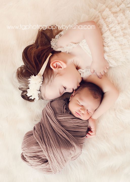 two babies are laying on top of each other in the middle of a white blanket