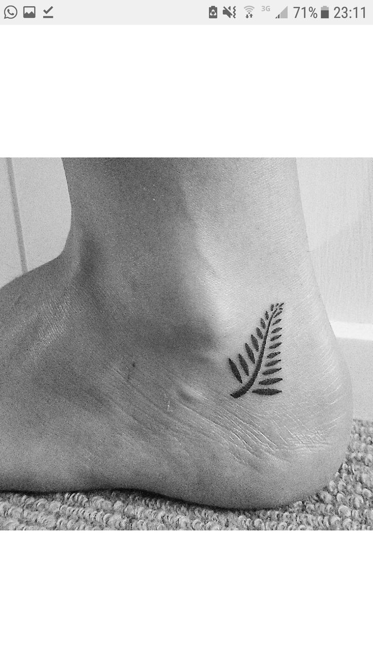 a black and white photo of a foot with a fern leaf tattoo on the side