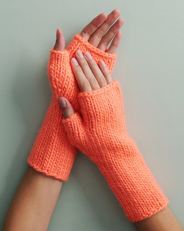 two hands wearing orange knitted gloves on top of each other