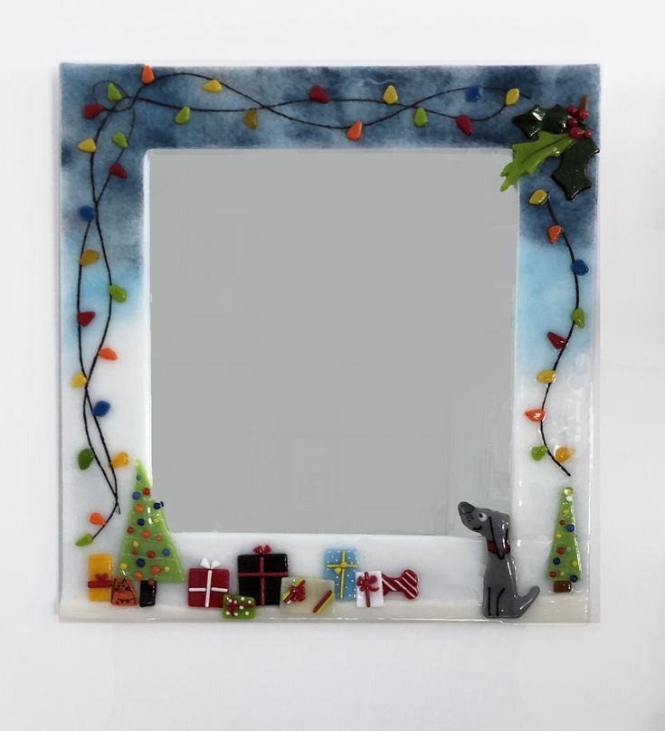 a decorative mirror with christmas decorations and lights on the bottom, in front of a white wall