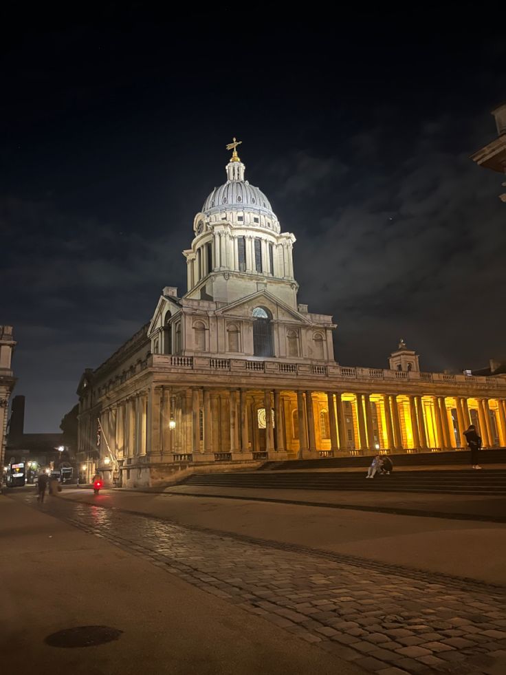 an old building lit up at night with people walking around