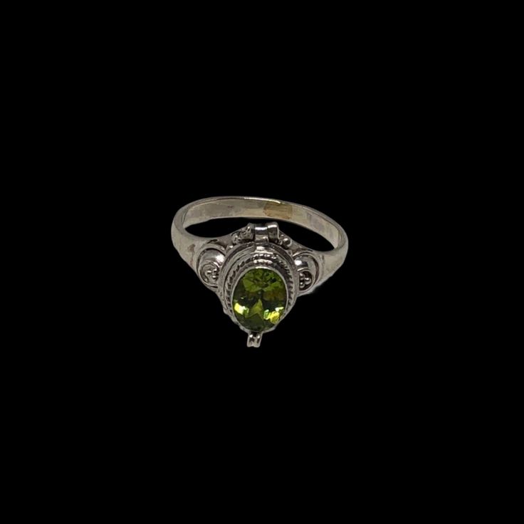 a ring with a green stone in the center on a black background, it is lit up