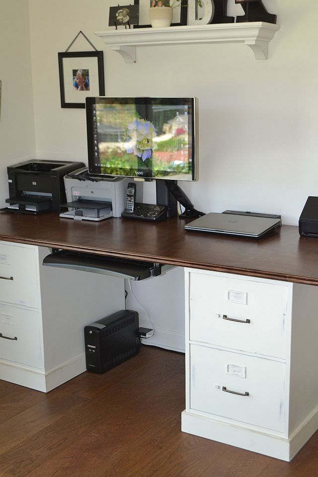 a desk with two computers on top of it and other office equipment in front of the monitor