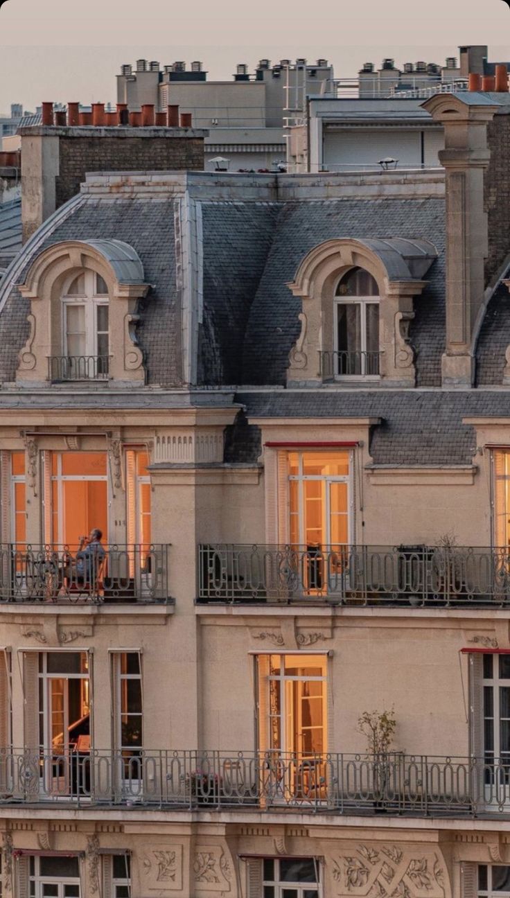 an apartment building with lots of windows and balconies on the top floor at dusk