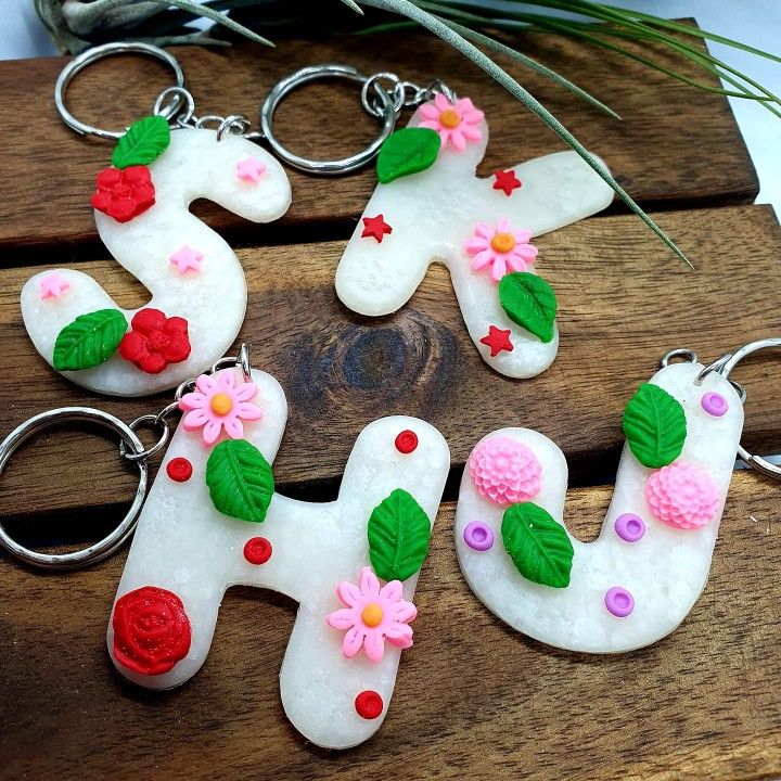 four decorated key chains sitting on top of a wooden table next to flowers and leaves