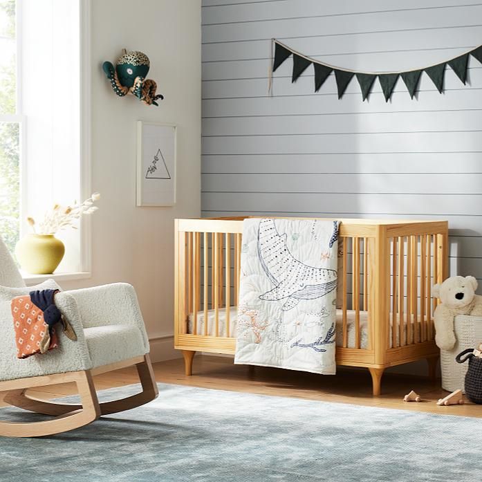 a baby's room with a rocking chair, crib and stuffed animals on the floor