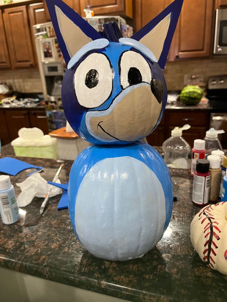 a blue and white cat statue sitting on top of a counter next to a baseball